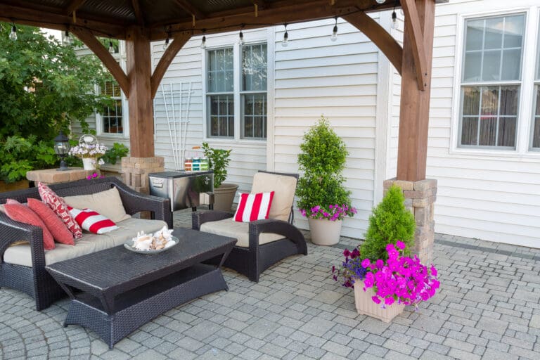 Outdoor living space on a brick patio with covered gazebo and comfortable furniture with colorful striped cushions