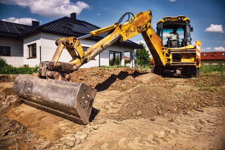 Excavator working at house construction site - digging foundations for modern house. Beginning of house building. Earth moving and foundation preparation
